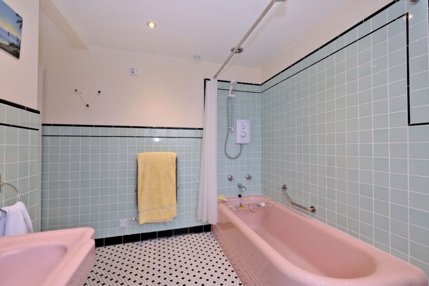 1970s style bathroom in The Graylings, fitted with a pink suite and light blue wall tiles.