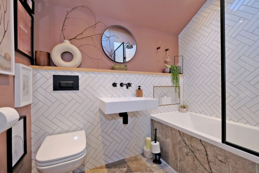 The bathroom has zigzagging white wall tiles and muted neutral colours.