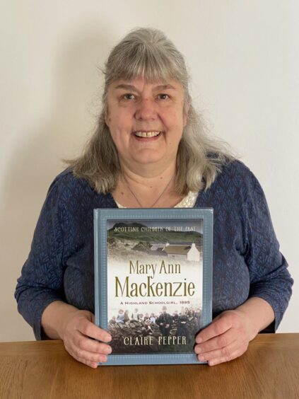 Author Claire Pepper holding her book, Mary Ann Mackenzie, A Highland Schoolgirl 1895.