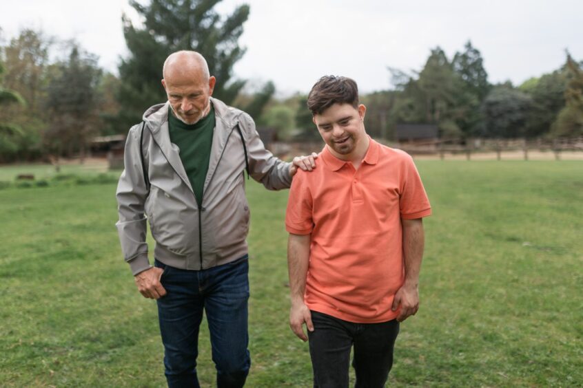 support worker walks outdoors with a young man with special needs 