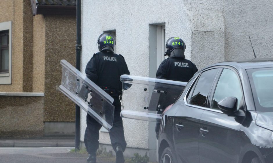 Police with riot shields during armed siege on Madras Street in Inverness.