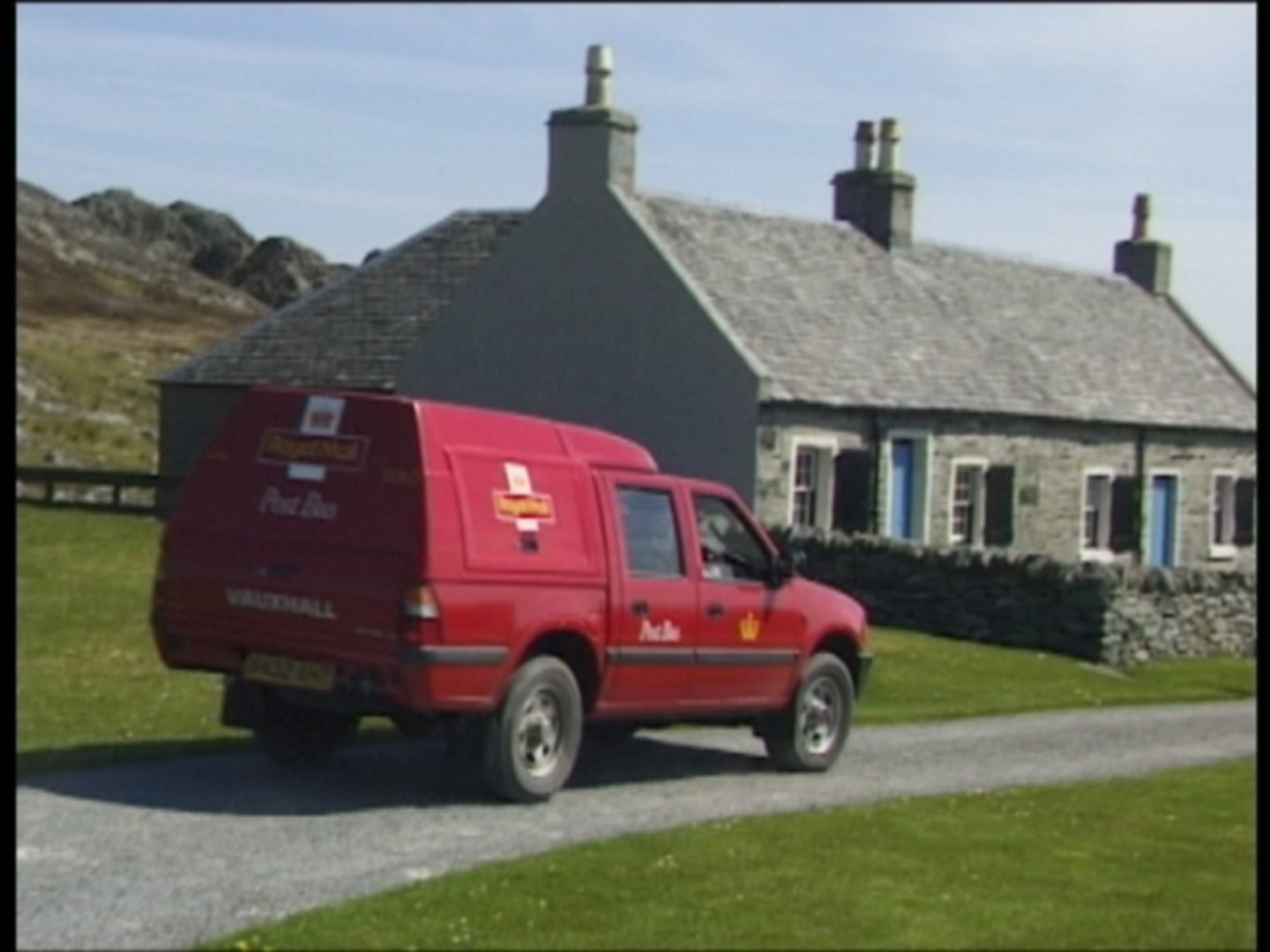 A post bus beside a home on its rounds on Oronsay. 