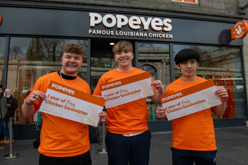 Josh, Nathan and Vincent hold up their certificates decked out in their Popeyes T-shirt.
