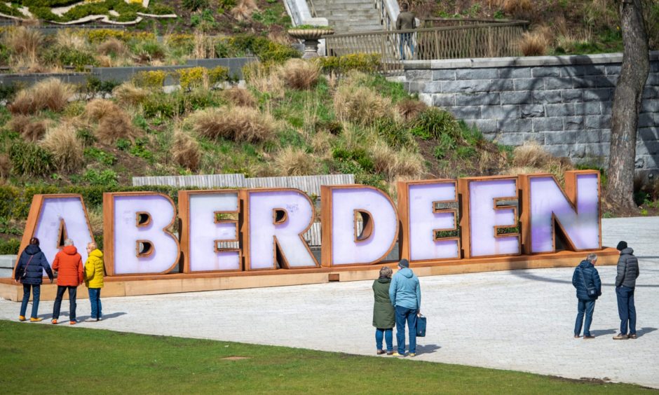 Cruise ship visitors in front of the Aberdeen sign at Union Terrace Gardens.