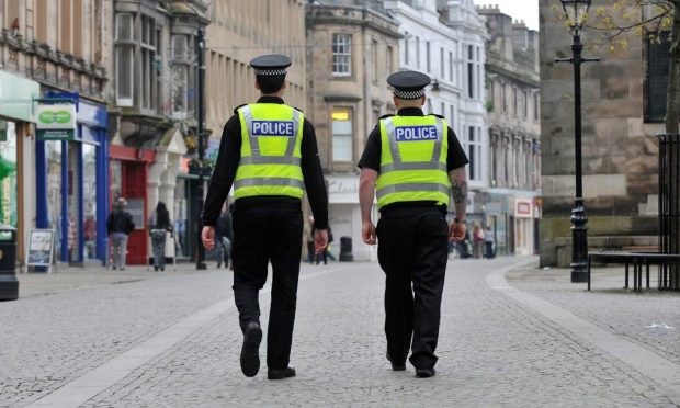 Two police officers walking on Elgin High Street away from camera.