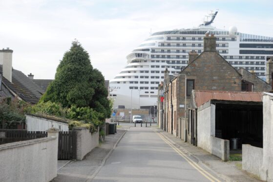 Houses dwarfed by a huge cruise ship in Invergordon. Image: Sandy McCook.