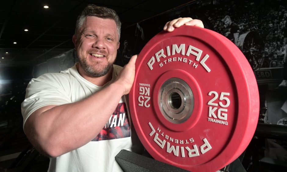 Luke Stoltman smiling holding weight.