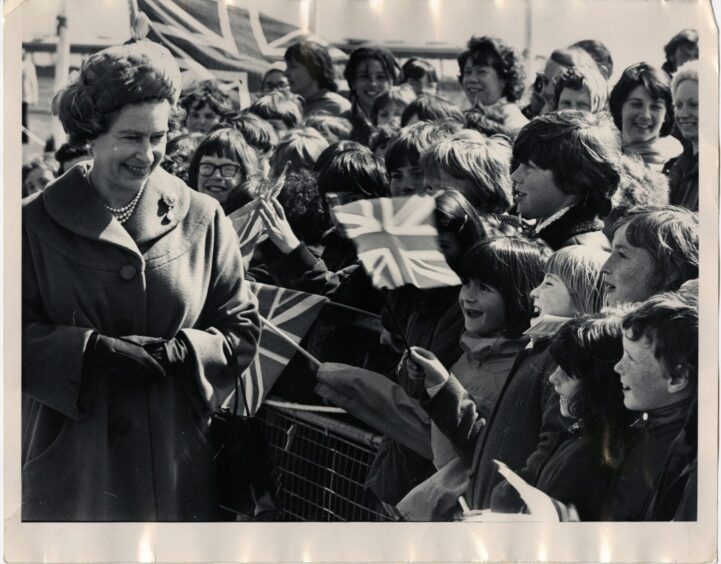 Queen Elizabeth greets flag-waving children during her walkabout. 