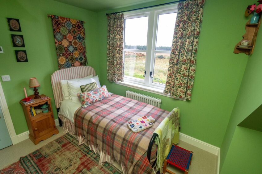 One of the bedrooms with plaid and floral patterns and bright green walls