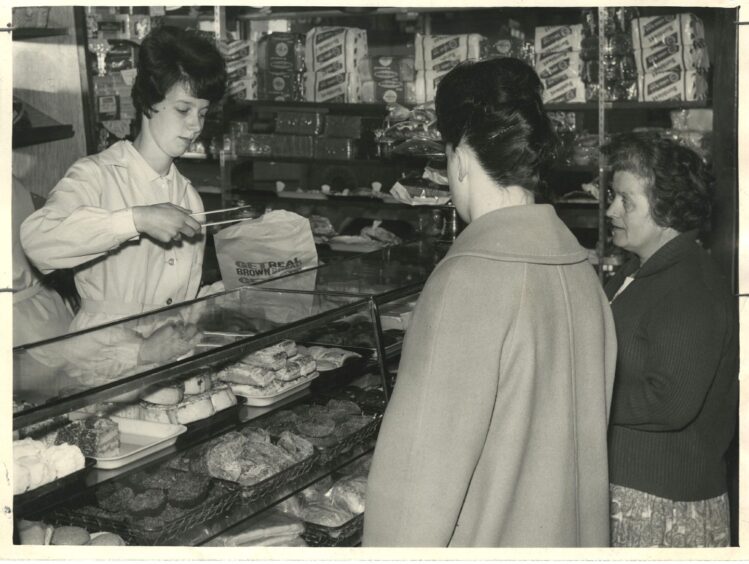  Linda Sim, an Aberdeen shop assistant, uses tongs when serving customers in a West End baker's shop during the typhoid outbreak.