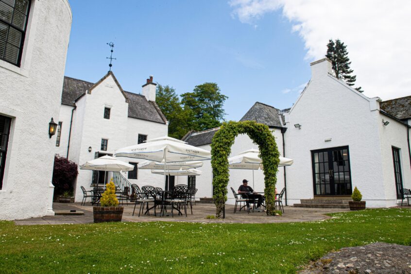 The exterior of Maryculter House Hotel with covered tables on a patio