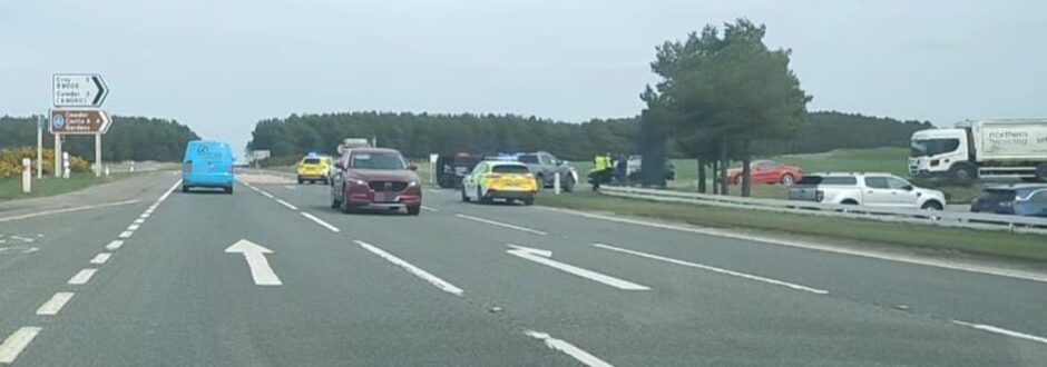 Police vehicles and cars block a cross junction on the A96 following a crash.
