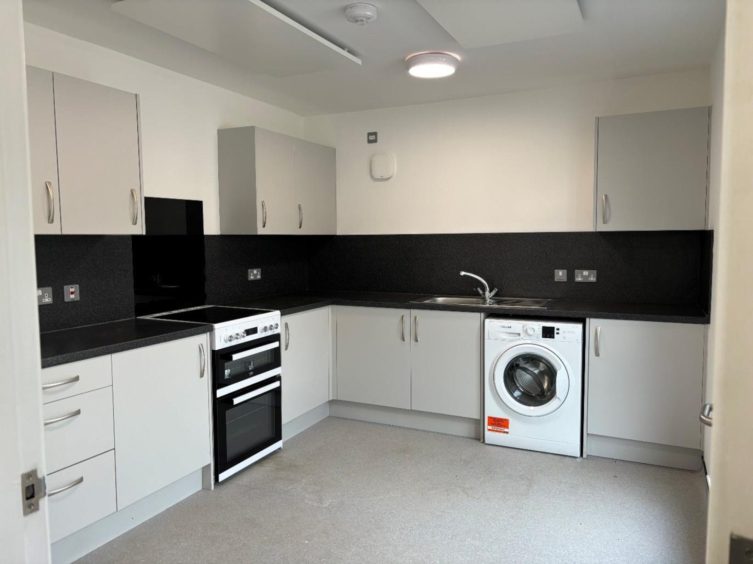 A fully fitted kitchen with cooker and washing machine.