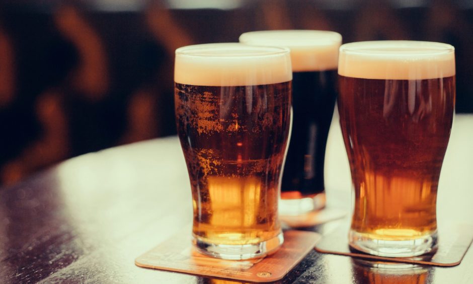 Three full pint glasses sitting on a table