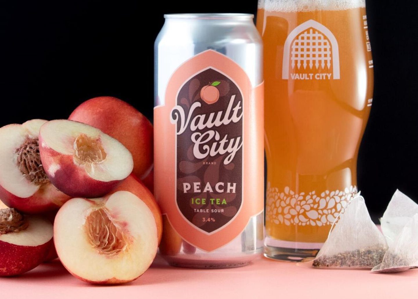 Vault City's Peach Ice Tea sour table beer, next to some peaches and black tea. 