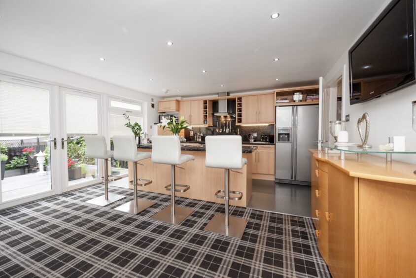 The open plan kitchen in the aberdeen townhouse for sale. It features a kitchen island with four modern barstools