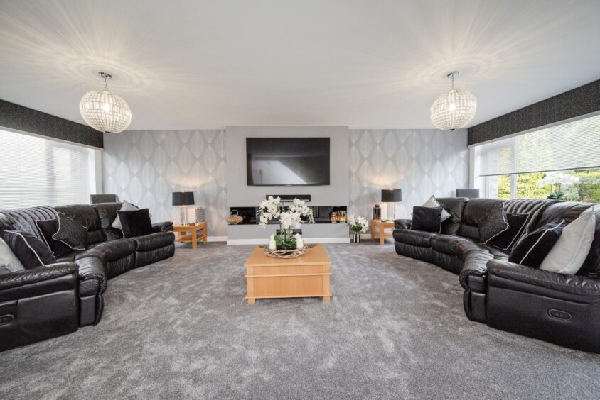 The spacious lounge in the aberdeen townhouse for sale with a grey and black theme and wooden accents