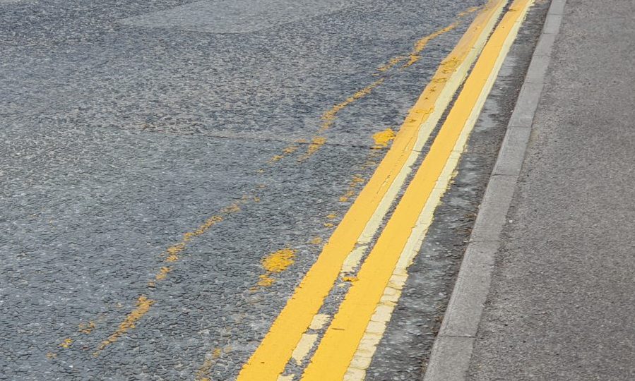 Double yellow lines with smears of yellow paint on the road. 
