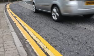 Silver car driving past the new double yellow lines.