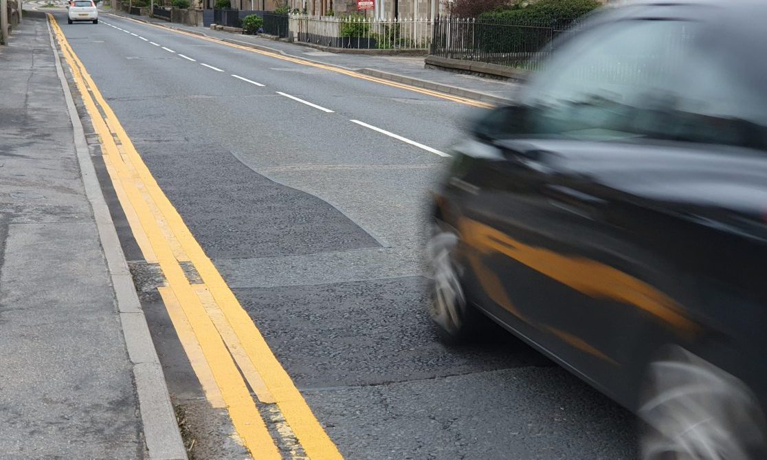 Dark car driving past extremely thick yellow lines. 