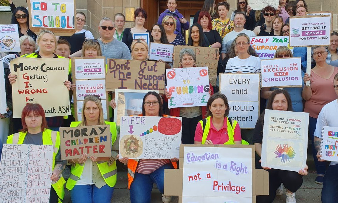 Parents holding up ASN protest banners on Moray Council HQ steps.