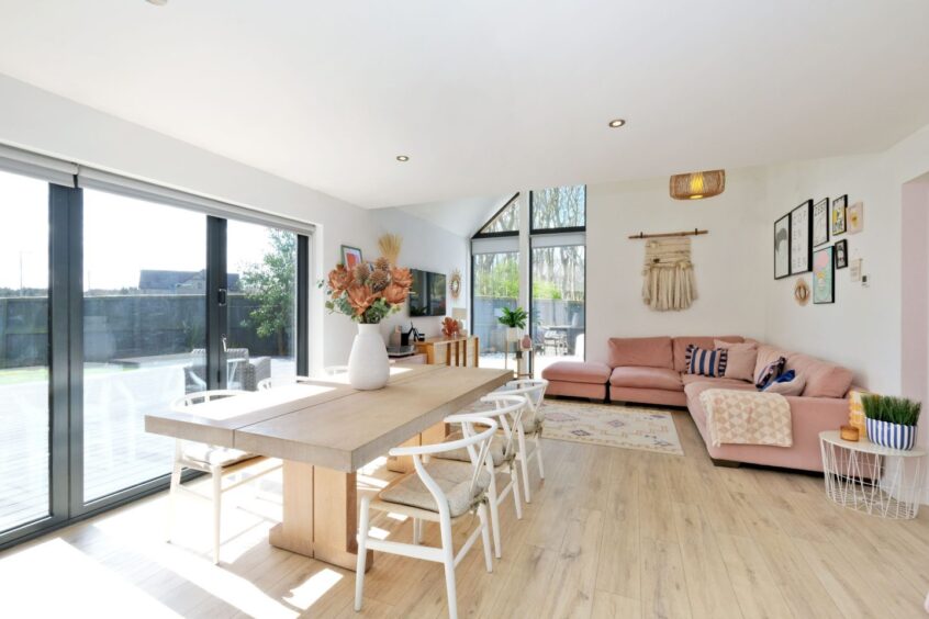 Open-plan living and dining area in the house for sale in Balmedie, featuring large floor-to-ceiling windows.