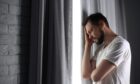 Lonely depressed man near window at home