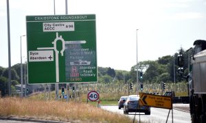 Green Craibstone Roundabout sign as cars travel along the route.