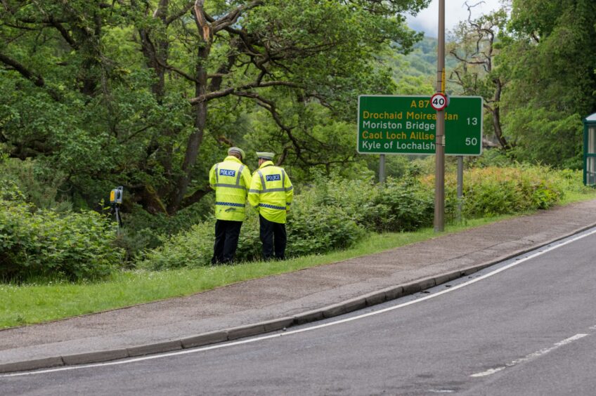 Two police officers standing on grass verge near River Garry