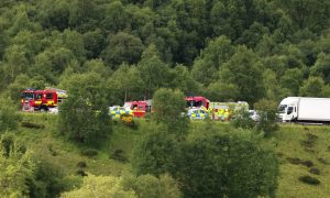 Fire engines and police vehicles behind the trees edging the A9