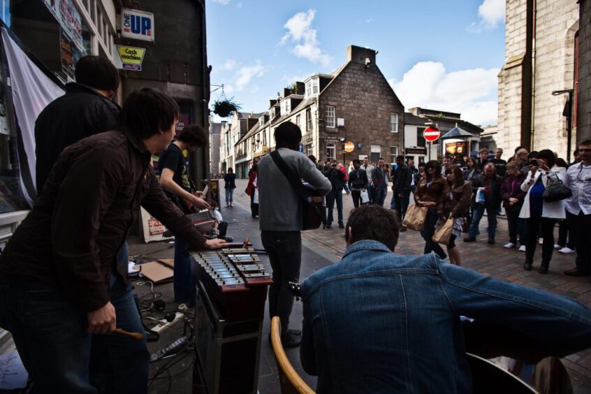 IndianRedLopez playing to a crowd on Belmont Street in Aberdeen
