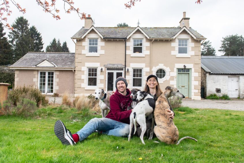 James and Holly sitting outside new home with their dogs 