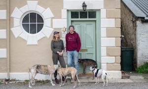 James and Holly with their four dogs standing outside their front door
