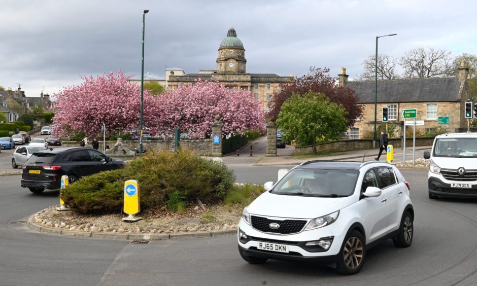 Cars on A96 roundabout in Elgin with Dr Gray's Hospital behind.