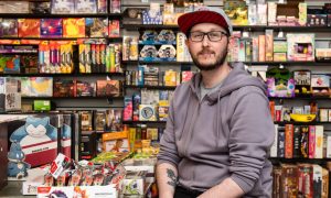 Peter Ralston behind the till at The Pop Shop surrounded by merchandise.