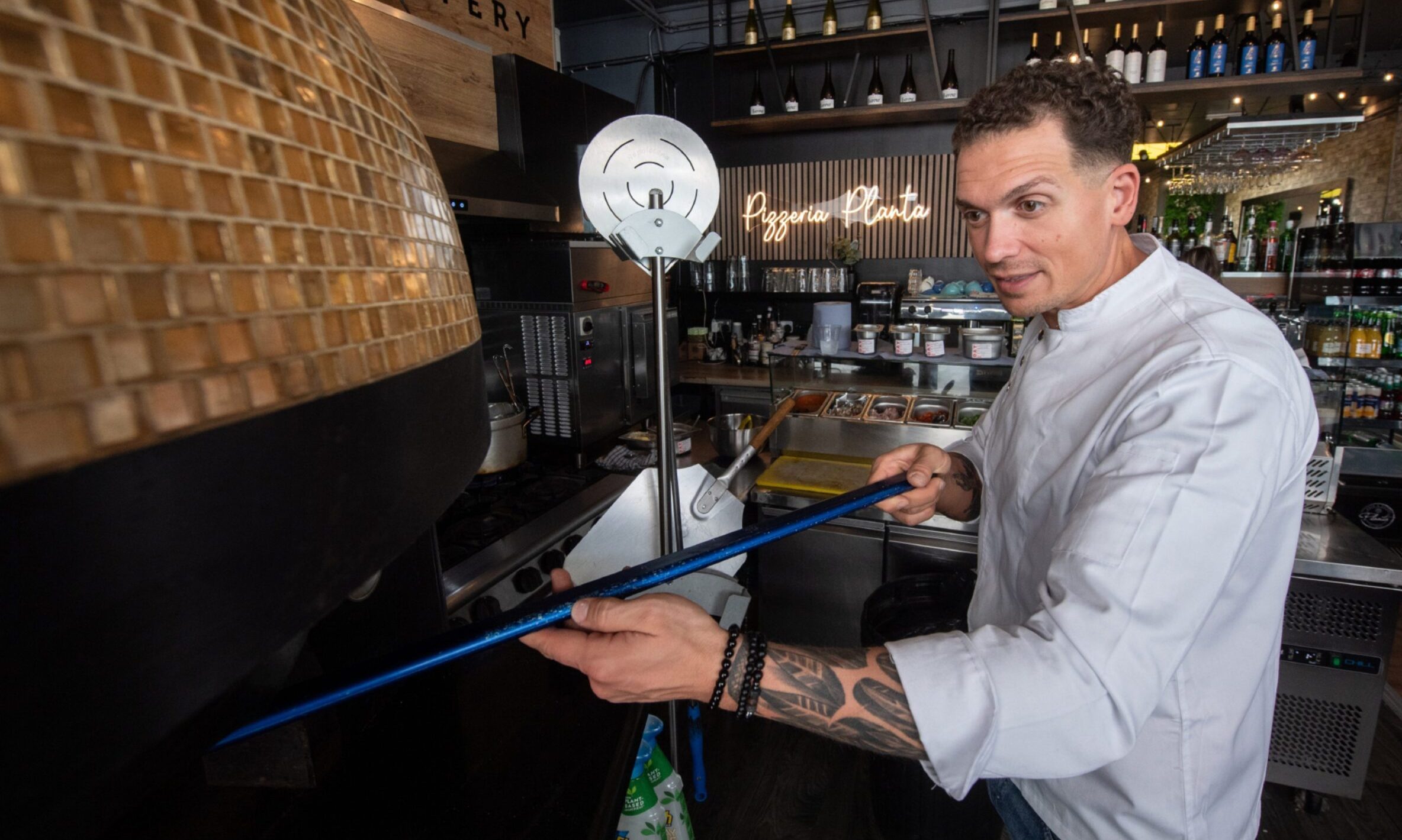 Marius Puscas sliding a pizza into the Planta pizza oven. 