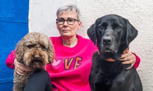 Jo Keown pictured centre with arms round dog on either side of her.