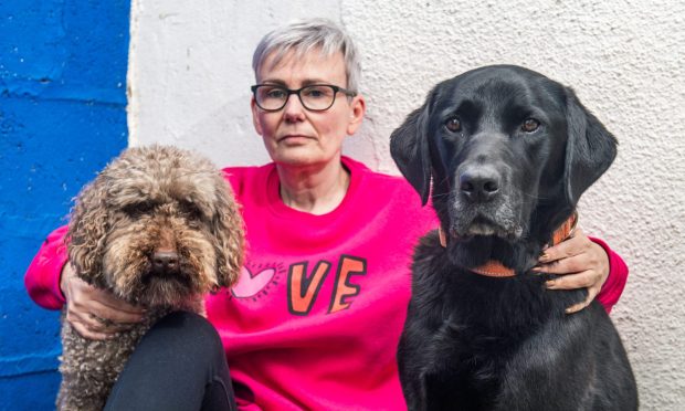 Jo Keown pictured centre with arms round dog on either side of her.