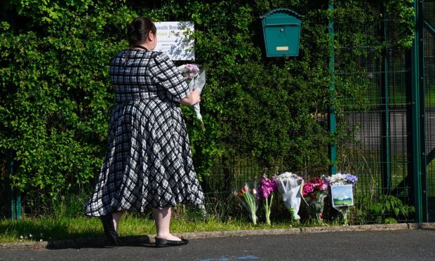 A mourner leaves a floral tribute to Ivy Mae Ross at the gates of the Plymouth Brethren Church in Balmedie on Thursday. Image:Kenny Elrick/DC Thomson