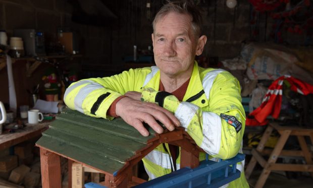 Tam Mitchell leans on one of his bird tables in his workshop