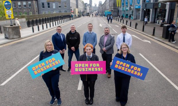 Union Street traders pose at the top of the high street with "city centre open for business" posters.