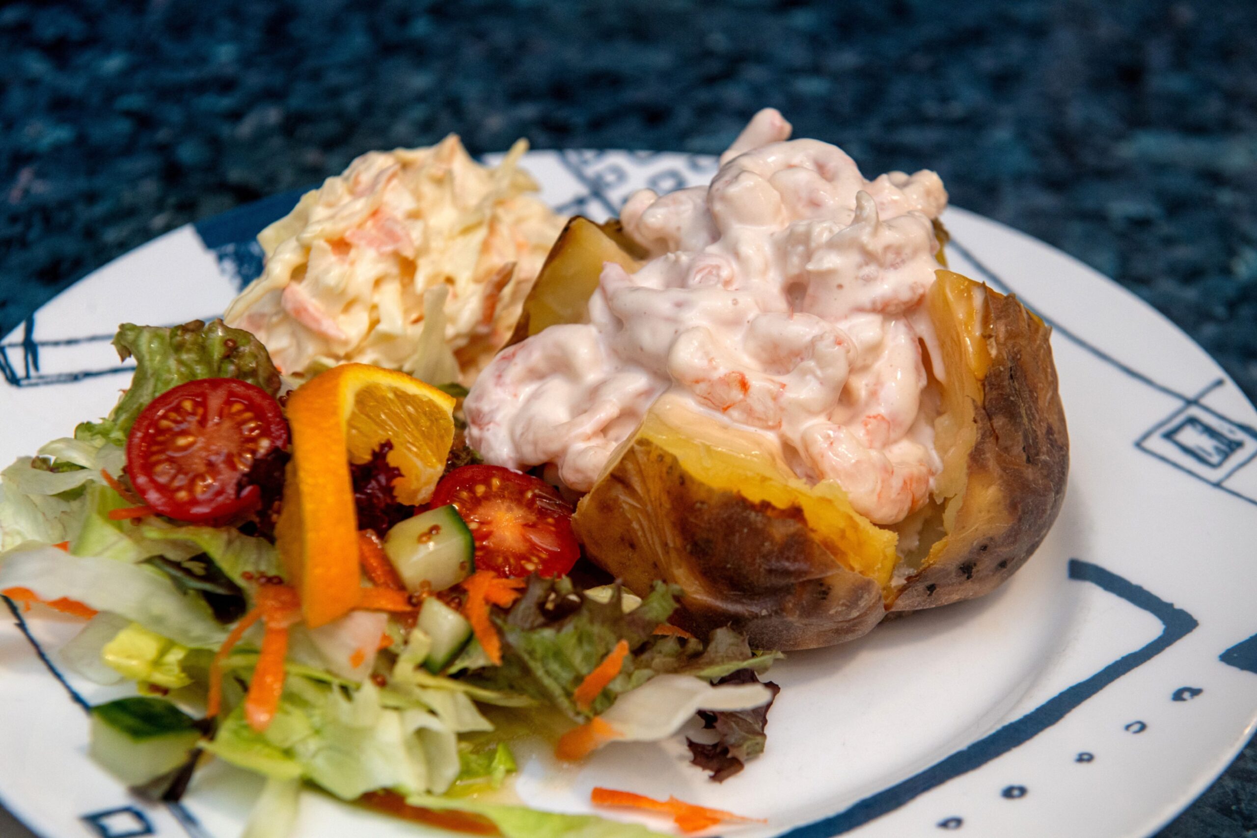 A baked potato topped with prawn Marie Rose sauce and served with salad and coleslaw.