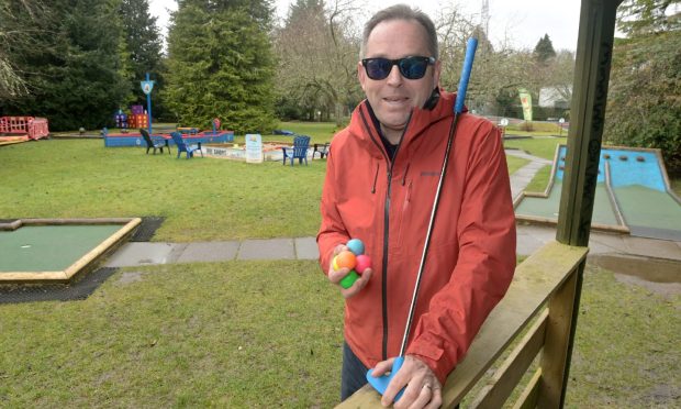 Gus MacDonald holding a club and balls at Inverness Crazy Golf.