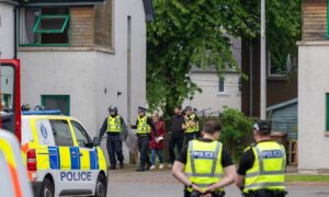 Police with shields and helmets can be seen outside the flat in Mill Court, Inverness. Image Jasperimage.