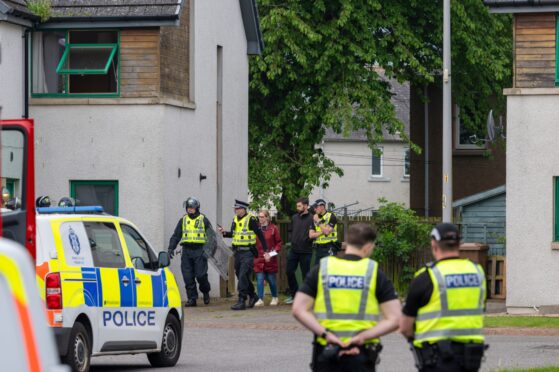 Police with shields and helmets can be seen outside the flat in Mill Court, Inverness. Image Jasperimage.