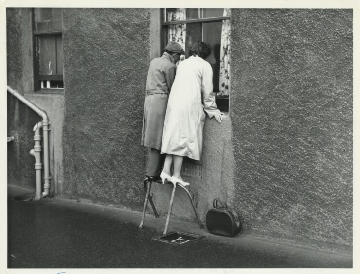 Families look at loved ones through the hospital window.