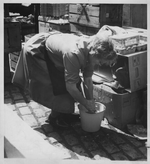 A woman washes her hands in a bucket in an egg store in Aberdeen during the typhoid outbreak.