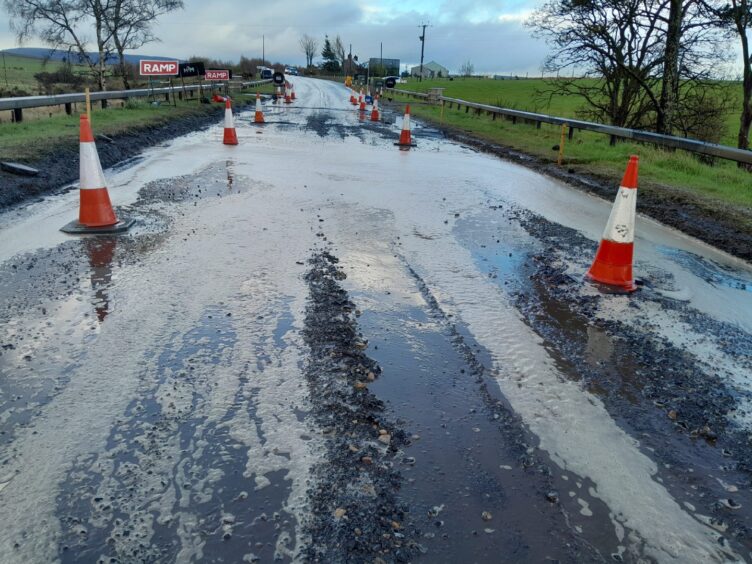 Cones line a dug-up section of the A96 amidst roadworks.