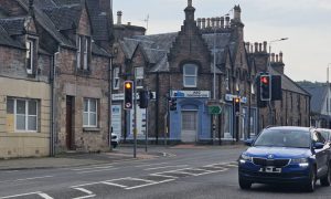 Vehicles travelling on Tomnahurich Street in Inverness near traffic lights.
