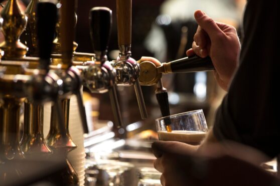 Grab yourself a drink. Image: Shutterstock
closeup of a bartender pouring a dark stout beer in tap with subject and focus on the right